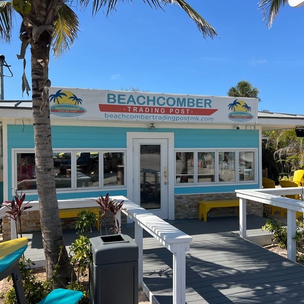 The Beachcomber Trading Post Restaurant, a vibrant blue building with a white sign, under a clear sky.