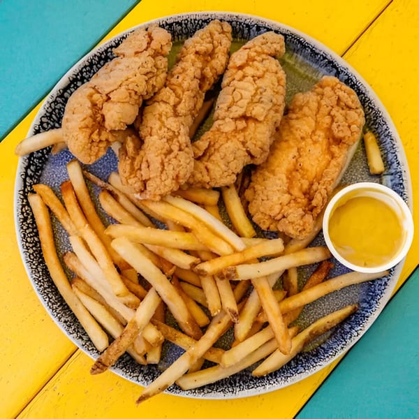A plate of crispy chicken tenders and golden french fries with a side of honey mustard.