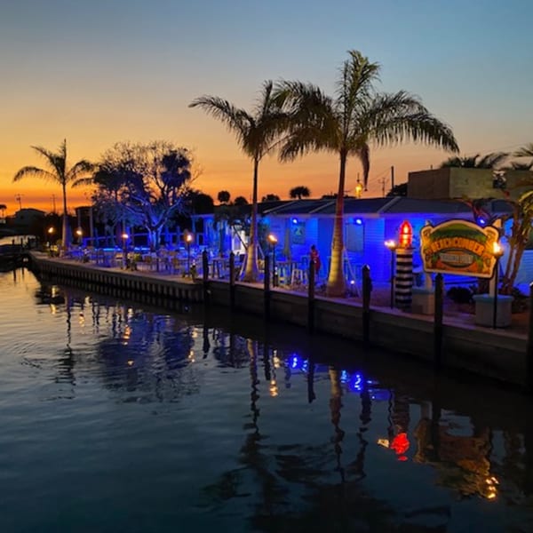 Beachcomber Trading Post Restaurant at sunset, with blue lights reflecting on the water.