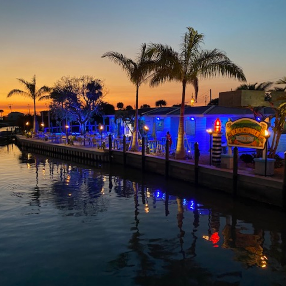 Beachcomber Trading Post Restaurant at sunset, with blue lights reflecting on the water.