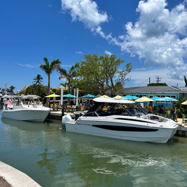 Boats docked at Beachcomber Trading Post Restaurant, with outdoor seating under colorful umbrellas.